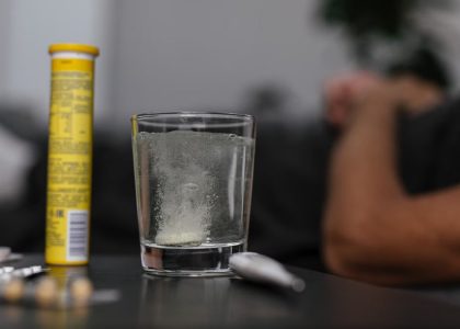 Effervescent tablet dissolving in glass, surrounded by medications, provides a healthcare-focused scene.